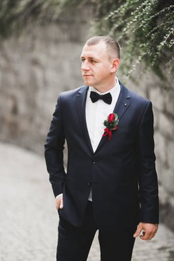 Yaka çiçeğiyle poz veren mutlu yakışıklı damat.