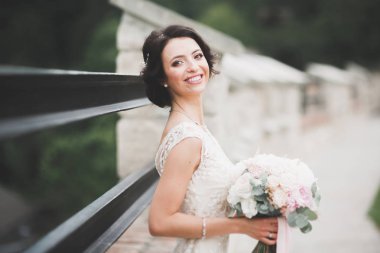 Parkta poz veren zarif beyaz elbiseli güzel gelin.