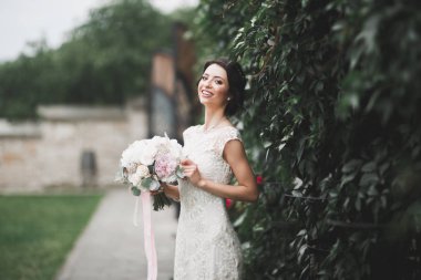 Parkta poz veren zarif beyaz elbiseli güzel gelin.