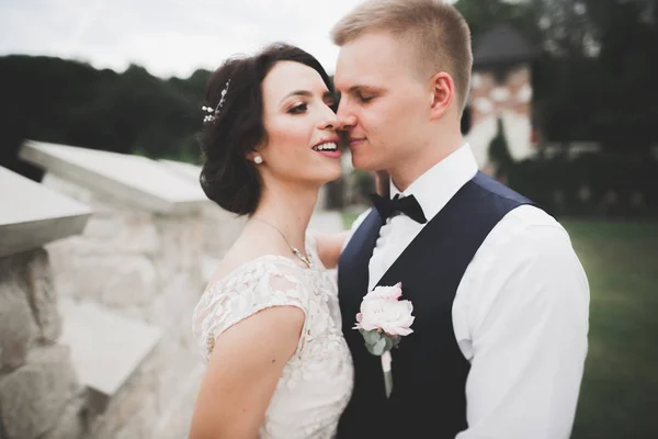 Stilvolles Brautpaar spaziert am Hochzeitstag mit Blumenstrauß durch den Park — Stockfoto