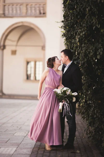 Beautiful couple, man, girl with long pink dress posing in old castle near columns. Krakow Vavel — Stock Photo, Image