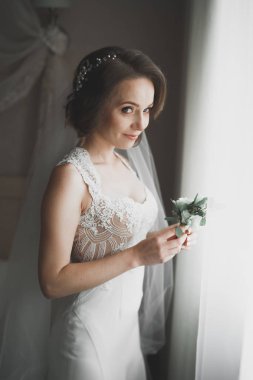 Cüppeli muhteşem gelin bir odada düğün töreni için poz veriyor ve hazırlanıyor.