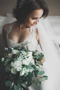 Cüppeli muhteşem gelin bir odada düğün töreni için poz veriyor ve hazırlanıyor.