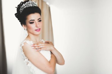 Cüppeli muhteşem gelin bir odada düğün töreni için poz veriyor ve hazırlanıyor.