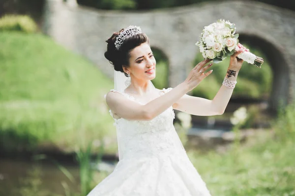 美しい豪華な若い花嫁でウェディングドレスポージングで公園 — ストック写真