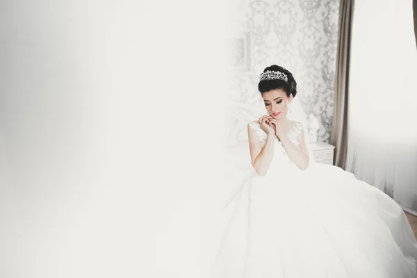 Hermosa novia con vestido de novia de moda con plumas con maquillaje de lujo deleite y peinado, estudio sesión de fotos interior — Foto de Stock