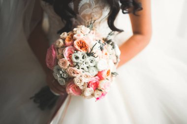 Gelin çiçekli büyük ve güzel bir düğün buketi tutuyor.
