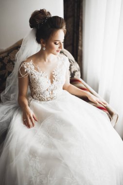Cüppeli muhteşem gelin bir odada düğün töreni için poz veriyor ve hazırlanıyor.