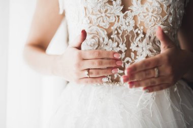 Cüppeli muhteşem gelin bir odada düğün töreni için poz veriyor ve hazırlanıyor.