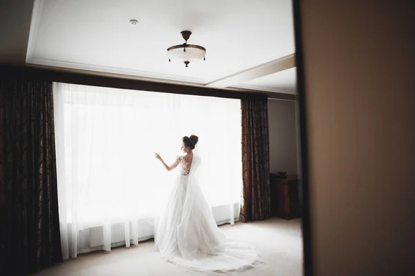 Preciosa novia en bata posando y preparándose para la ceremonia de boda cara en una habitación — Foto de Stock