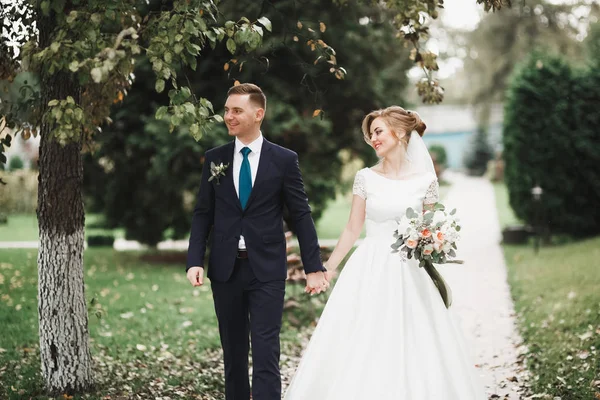 멋진 신혼 부부들 이 꽃다발을 들고 결혼식 날 공원을 거닐고 있다 — 스톡 사진