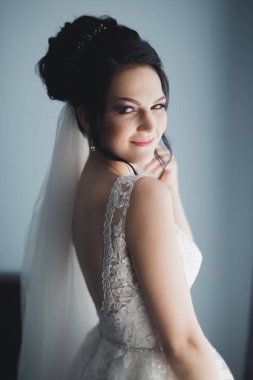 Cüppeli muhteşem gelin bir odada düğün töreni için poz veriyor ve hazırlanıyor.