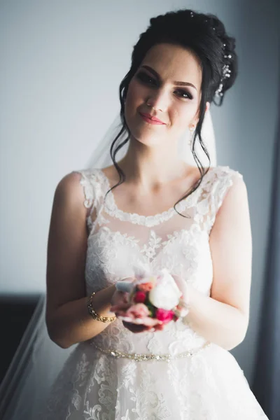 Gyönyörű menyasszony köntösben pózol és készül az esküvői szertartás arc egy szobában — Stock Fotó