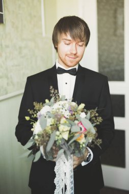 Yaka çiçeğiyle poz veren mutlu yakışıklı damat.