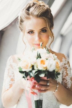 Çekici gelinin portresi, uzun saçlı, büyük buketli poz veren.