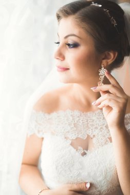 Beyaz elbiseli lüks gelin düğün törenine hazırlanırken poz veriyor.