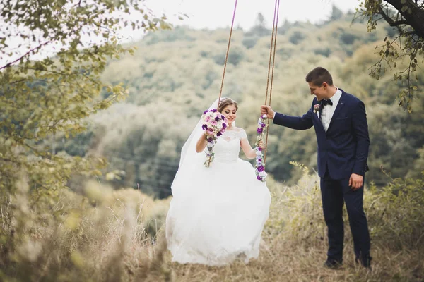 Romantico, fiaba, felice coppia di sposi che si abbraccia e si bacia in un parco, alberi sullo sfondo — Foto Stock