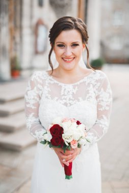 Çekici gelinin portresi, uzun saçlı, büyük buketli poz veren.