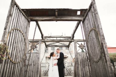 Güzel, romantik bir düğün. Yeni evliler. Eski kalenin yakınlarında sarılıyorlar.