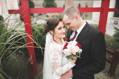 Güzel, romantik bir düğün. Yeni evliler. Eski kalenin yakınlarında sarılıyorlar.