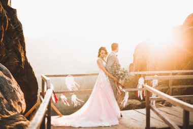 Güzel bir düğün çifti mükemmel bir manzarayla dağda öpüşüyor ve sarılıyor.