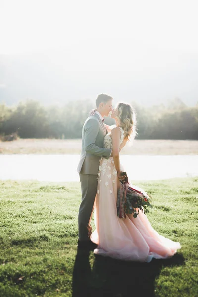 Elegante elegante sposa bruna felice e splendido sposo sullo sfondo di un bellissimo fiume in montagna — Foto Stock