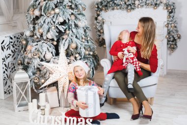 Anne ve kızları küçük kızların doğum günü hediyelerini açıyorlar.