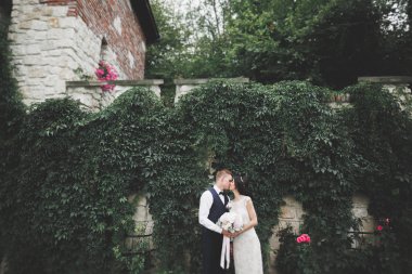 Yeni evli çiftimiz düğün günlerinde ellerinde buketle parkta yürüyorlar.