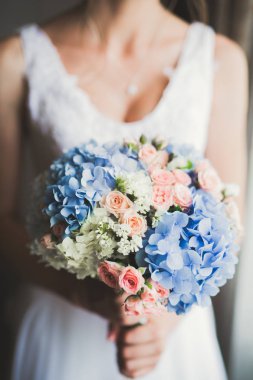 Cüppeli muhteşem gelin bir odada düğün töreni için poz veriyor ve hazırlanıyor.