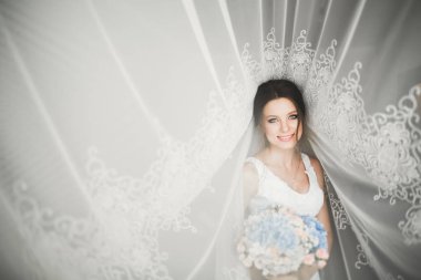 Beyaz elbiseli lüks gelin düğün törenine hazırlanırken poz veriyor.