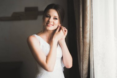 Cüppeli muhteşem gelin bir odada düğün töreni için poz veriyor ve hazırlanıyor.