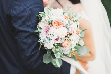 Gelin çiçekli büyük ve güzel bir düğün buketi tutuyor.