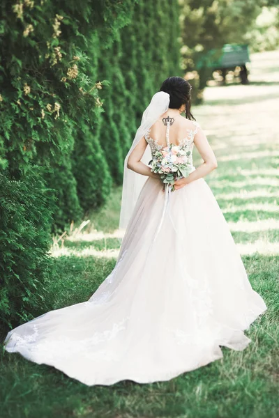 Mooie luxe jonge bruid in trouwjurk poseren in park — Stockfoto
