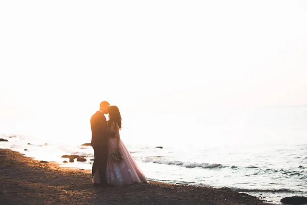 Boda pareja, novio, novia con ramo posando cerca del mar y el cielo azul — Foto de Stock