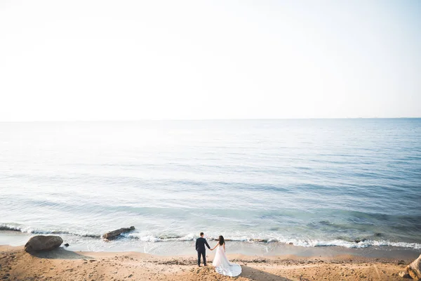 Matrimonio coppia, sposo, sposa con bouquet posa vicino al mare e cielo blu — Foto Stock
