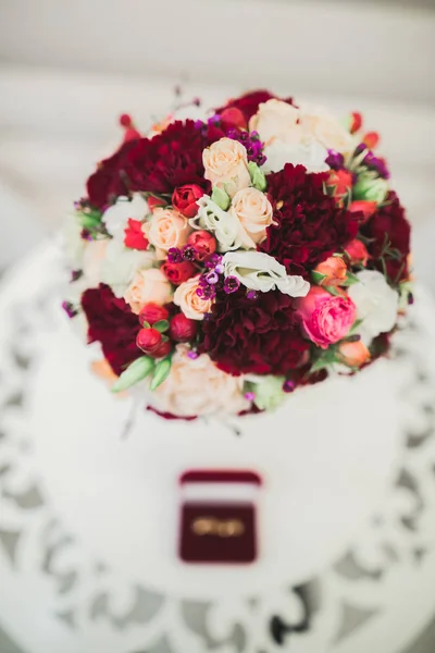 Beautiful toned picture with wedding rings against the background of a bouquet of flowers — Stock Photo, Image