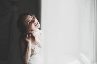 Cüppeli muhteşem gelin bir odada düğün töreni için poz veriyor ve hazırlanıyor.