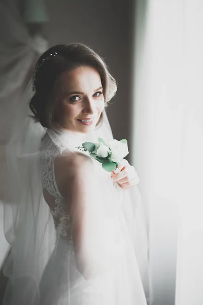 Великолепная невеста в халате позирует и готовится к свадебной церемонии лицо в комнате — стоковое фото