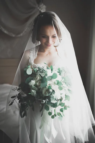 Preciosa novia en bata posando y preparándose para la ceremonia de boda cara en una habitación —  Fotos de Stock