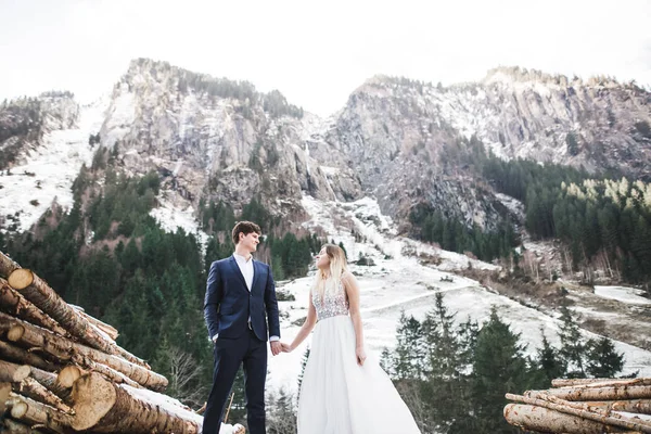 Hermosa pareja joven en las montañas de invierno. Paseo de invierno de los amantes. Hombre abrazando mujer —  Fotos de Stock