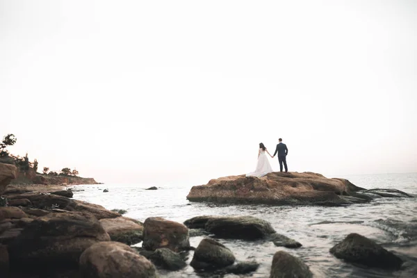 Boda pareja, novio, novia con ramo posando cerca del mar y el cielo azul — Foto de Stock