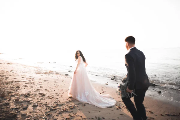 Esküvői pár, vőlegény, menyasszony csokorral pózol közel a tenger és a kék ég — Stock Fotó
