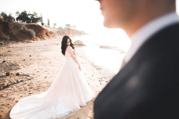 Svatební pár, ženich, nevěsta s kyticí pózující u moře a modrá obloha — Stock fotografie