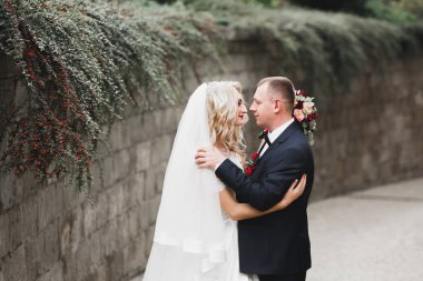 Yeni evli çift el ele tutuşurken parkta koşup zıplıyorlar.