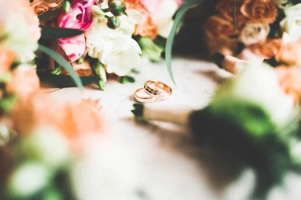 在一束鲜花的衬托下，有结婚戒指的美丽色调的照片 — 图库照片