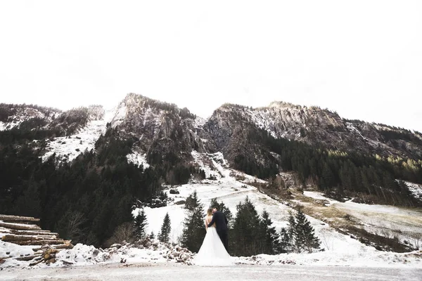 Hermosa pareja joven en las montañas de invierno. Paseo de invierno de los amantes. Hombre abrazando mujer —  Fotos de Stock