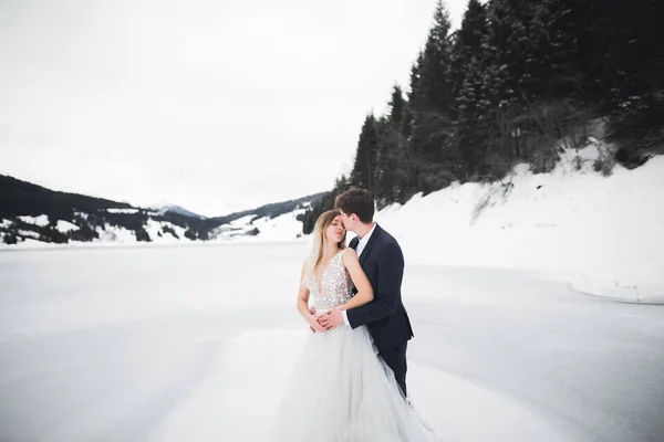 Joven pareja feliz besándose, montañas paisaje en la nieve en el fondo — Foto de Stock