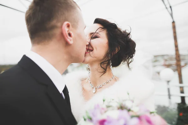 Härligt lyckligt bröllop par, brud med lång vit klänning poserar i vacker stad — Stockfoto