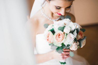 Gelin çiçekli büyük ve güzel bir düğün buketi tutuyor.