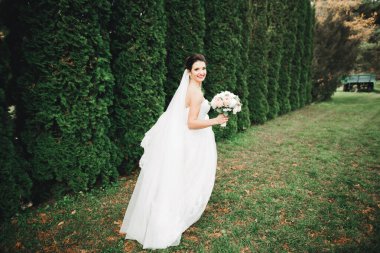 Parkta poz veren zarif beyaz elbiseli güzel gelin.